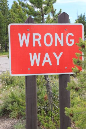 Red and white road sign stating "WRONG WAY" informing traffic not to go down the road the wrong wayの写真素材