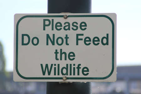 Sign on a post stating "Please Do Not Feed the Wildlife"の写真素材
