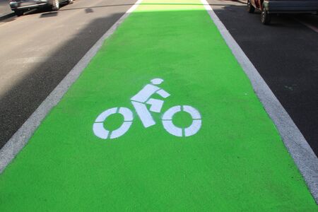 Green painted lane with a painted white bicycle indicating a cycle lane or bicycle routeの写真素材
