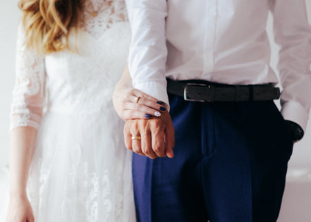 Wedding couple holding hands, close-up. Bride and groom holding handsの写真素材