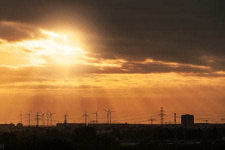 Sunset over the city and wind turbines in the rays of the setting sunの写真素材
