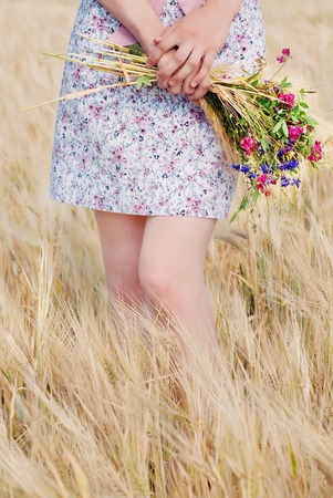Woman with Wild Flowers in the Wheat Field in Summer. Harmony and Femininityの写真素材