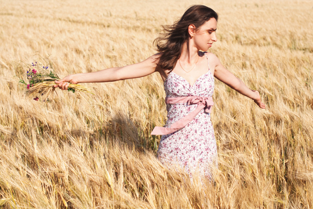 Woman with Wild Flowers in the Wheat Field in Summer. Harmony and Femininityの写真素材