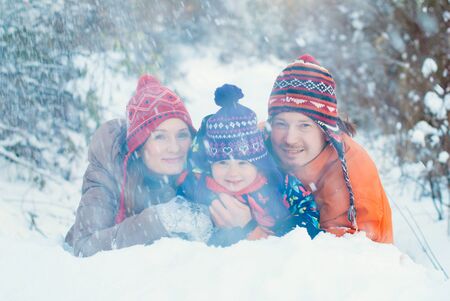 Winter Lifestyle Concept - Happy Family Having Fun in Winter Park - People playing with Snow Outdoor - Happiness Emotions - Flying Snowflakesの写真素材