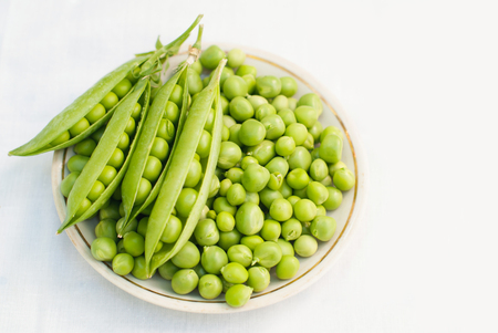 Green pea in a bowl of top view on white background with copy spaceの写真素材