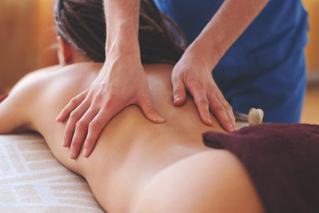 Close-up of masseur hands doing back massage - Healing Massage and body care - young woman getting...