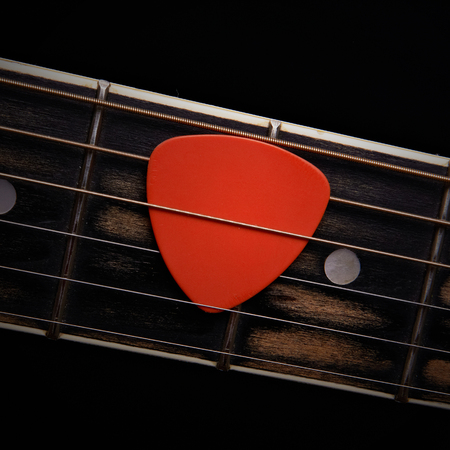 Orange guitar pick on the fingerboardの写真素材