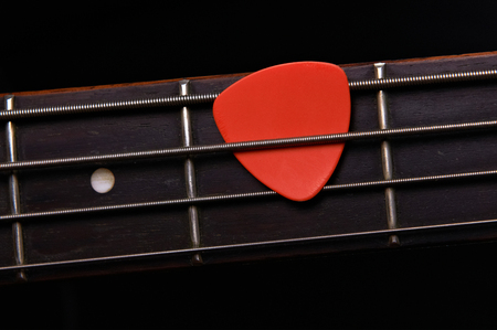 Orange guitar pick on the fingerboardの写真素材
