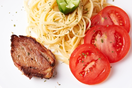 Pork with pasta and tomatoes on the tableの写真素材
