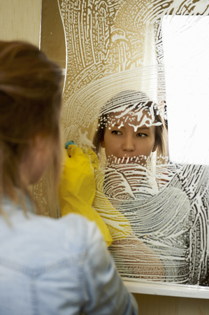 Pretty woman cleans  mirrorの写真素材