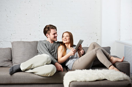 Romantic relaxed young couple using tablet computer on couchの写真素材