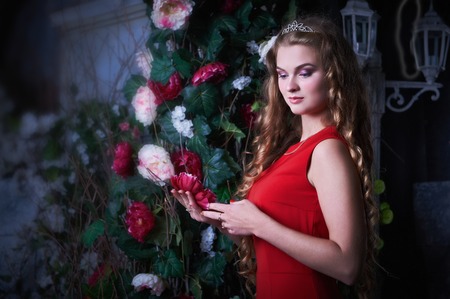 Beautiful princess in red dress sitting in a mystical gardenの写真素材