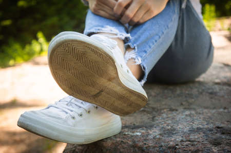 Female feet in jeans and sports shoes. Woman resting the walk.の写真素材