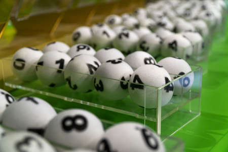 Many sets of game white balls with numbers for lottery on a green tableの写真素材