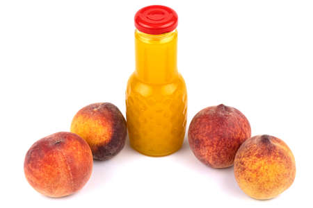 Peach juice bottle. Nearby are juicy, beautiful peaches. Studio photo on a white background.の写真素材