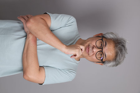 Asian man with glasses who is wearing a tshirt and crossed arms while having thinking expression.