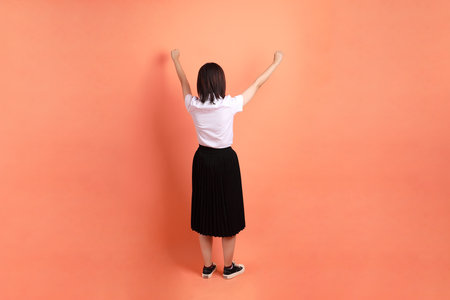 Cheerful female student in Thai university uniform with gesture of cheerful, excited, celebrating isolated on orange background. International Students' Day, World Students' Day. Gen Zの写真素材