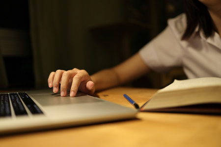 A young female student in a Thai university uniform sits at a desk in study, studying online with a laptop. International Students' Day, World Students' Day. Gen Z, E-learningの写真素材