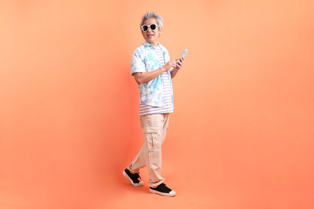 HAPPY SONGKRAN DAY. Asian tourist senior man in summer clothing with gesture of hand Holding mobile...