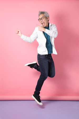 Asian energetic senior man with glasses posing  isolated on the brown background with casual clothes. mature man, Asian man. Elderly,  studio shot. Multiple emotions.の写真素材