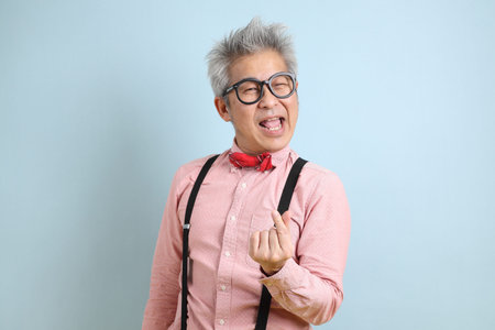 Asian senior man in black suspenders with red bow with gesture of  heart-shaped or mini heart...