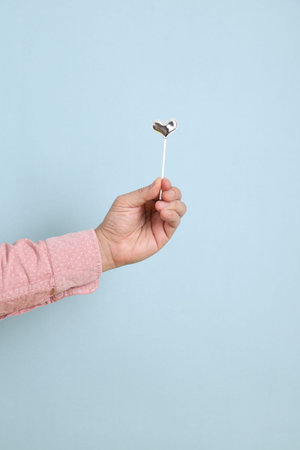 Hand of asian man with gesture of  holding mini heart-shaped isolated on blue background. St...