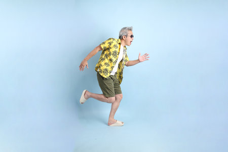 HAPPY SONGKRAN DAY. Asian tourist senior man in summer clothing with gesture of  Walking isolated on blue background. Songkran festival. Thai New Year's Day.の写真素材