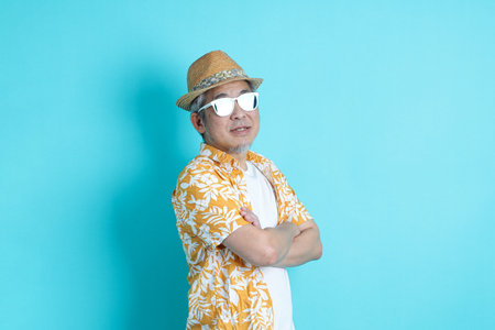 Portrait of Asian energetic senior man posing on blue background with travel clothes. mature man, Asian man. Elderly, Holiday, Travel. studio shot. Multiple emotions.の写真素材