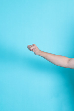Asian man's hand or hand gesture on a blue isolated backgroundの写真素材