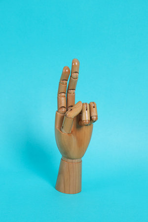 Hand of mannequin posing on isolated blue background. Symbol, Puppet.