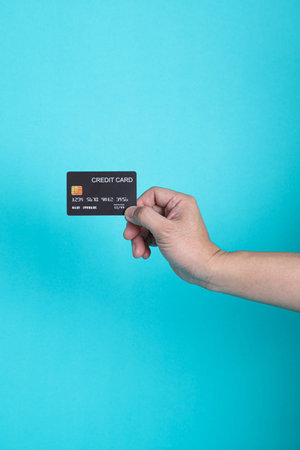 Male hand holds bank credit card isolated on blue background