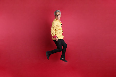 Happy Chinese new year. Asian Chinese energetic senior man wearing golden traditional cheongsam...