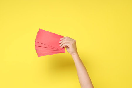 Happy Chinese new year. Asian Chinese senior man dress in white color with gesture of hand holding Chinese Red envelopes isolated on yellow background.  Vegetarian Festivalの写真素材