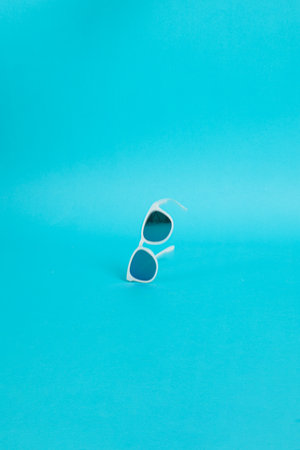 Modern sunglasses with white plastic frame isolated on blue background.の写真素材
