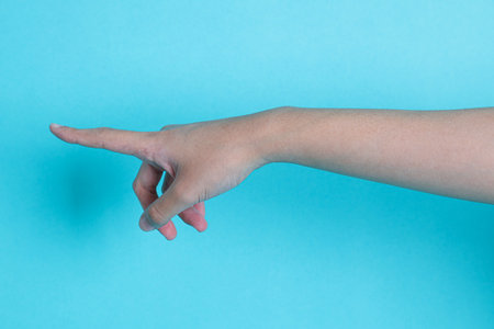 Asian women's hand or hand pointing  gesture on a blue isolated backgroundの写真素材