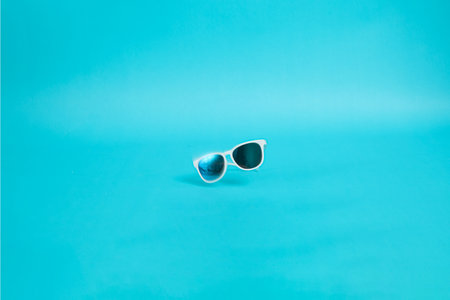 Modern sunglasses with white plastic frame isolated on blue background.の写真素材