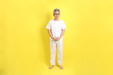 Chinese Vegetarian Festival (J festival)  senior man dress in white color with gesture of standing isolated on yellow background. Vegetarian Festival, Nine emperor god.の写真素材