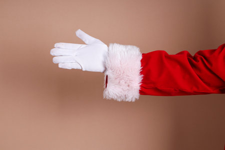 Hands of Santa Claus in his red suit posing in multiple gesture on brown isolated background.の写真素材