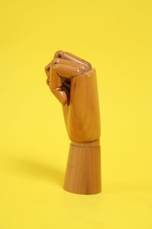 Hand of mannequin with multiple poses isolated on yellow background. Symbol, Puppet.