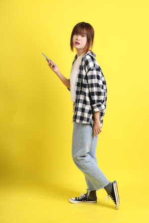 Asian college female student wearing plaid shirt with gesture of Holding mobile phone. Education, Studying abroad, Gen Z, E-learning.の写真素材