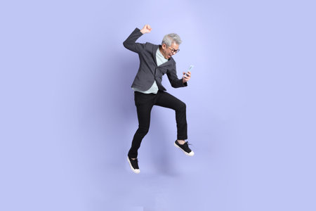 50s asian senior Businessman with glasses dressed in formal outfit with gesture of playing mobile...