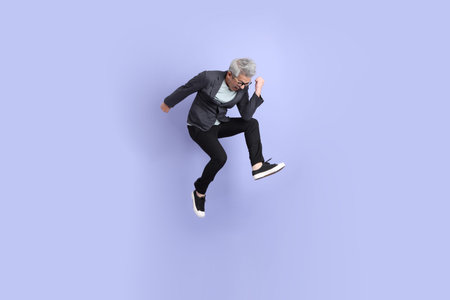 50s asian senior Businessman with glasses dressed in formal outfit with gesture of jumping isolated...