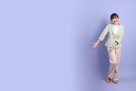 A young asian Businesswoman in formal outfit with gesture of pointing and greeting isolated on purple background. Gen Z, internship, Career, Officeの写真素材