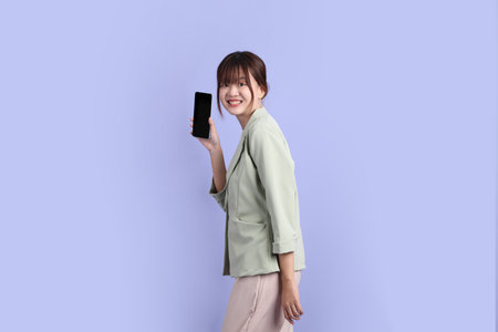 A young asian Businesswoman in formal outfit with gesture of Holding mobile phone isolated on purple...