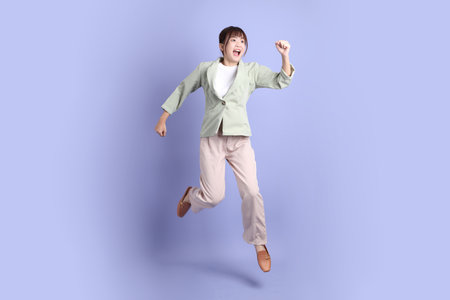 A young asian Businesswoman in formal outfit with gesture of jumping isolated on purple background. Gen Z, internship, Career, Officeの写真素材