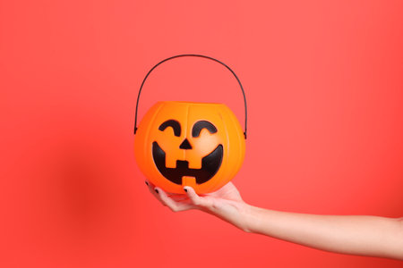 HAPPY HALLOWEEN DAY, female hand with black nails holding Jack-o-Lantern Pumpkin isolated on orange background.の写真素材