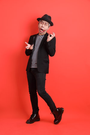 Asian senior man in Halloween costume with gesture of funny and Silly pose isolated on the orange background.の写真素材