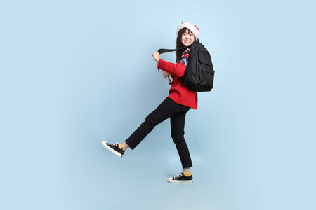 Asian female student wearing Christmas or winter clothes with Santa cap with gesture of holding a...