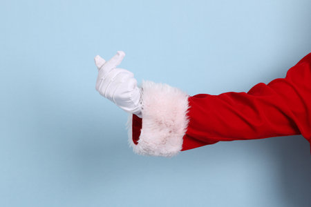 A close-up of a hand of Santa Claus with gesture of Heart-shaped, mini heart, love, isolated against a blue background. Merry Christmas.の写真素材