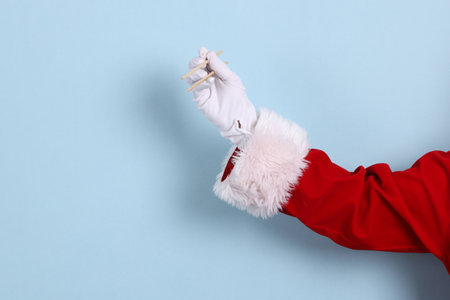A close-up of a hand of Santa Claus holding up wooden chopsticks , isolated against a blue background. Merry Christmas.の写真素材